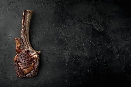 Grilled tomahawk beef steak set, on black stone background, top view flat lay, with copy space for text