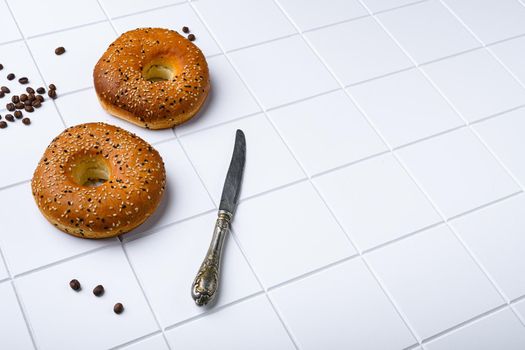Fresh Bagels with Sesame, on white ceramic squared tile table background, with copy space for text