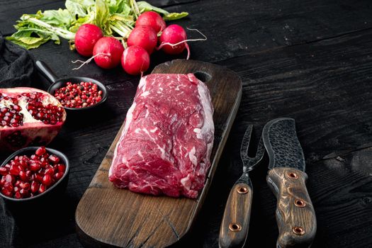 Fresh and raw beef meat. Whole piece of tenderloin with steaks and spices ready to cook set, on black wooden table background, with copy space for text