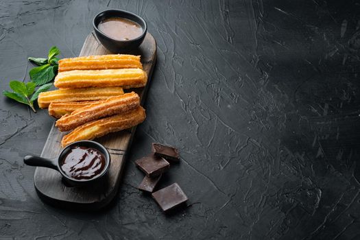 Churros with caramel, Traditional Spanish cusine, on black background with space for text, copyspace