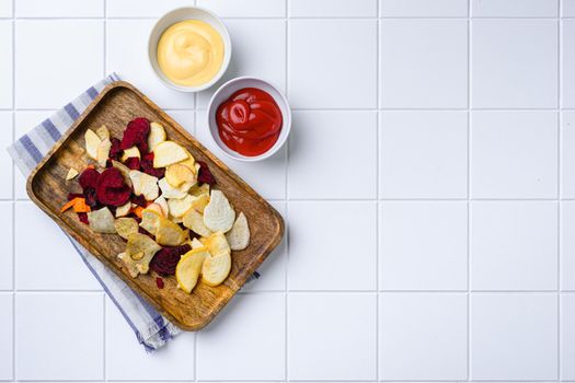 Dried vegetables chips set, on white ceramic squared tile table background, top view flat lay, with copy space for text