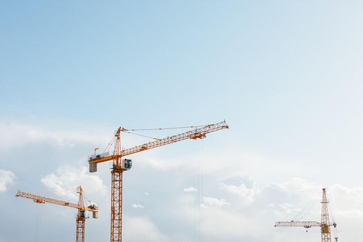 building cranes at the construction site on blue sky background