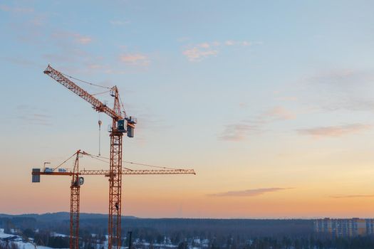 building cranes on the construction site at sunset background