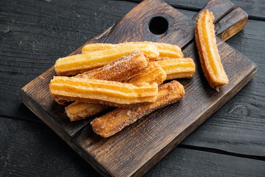 Tasty churros with chocolate caramel sauce set, on black wooden table background