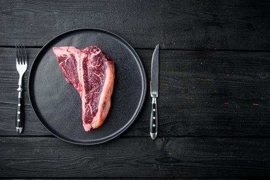 Sirloin beef meat marbled steak set, T bone cut, on black wooden table background, top view flat lay, with copy space for text