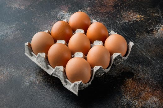 Brown eggs in carton box tray set, on old dark rustic background