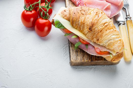 Fresh croissant or sandwich with salad, ham, jamon, prosciutto set, with herbs and ingredients, on white stone background, with copy space for text