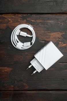 Accessories for a smartphone, charger set, on old dark wooden table background, top view flat lay