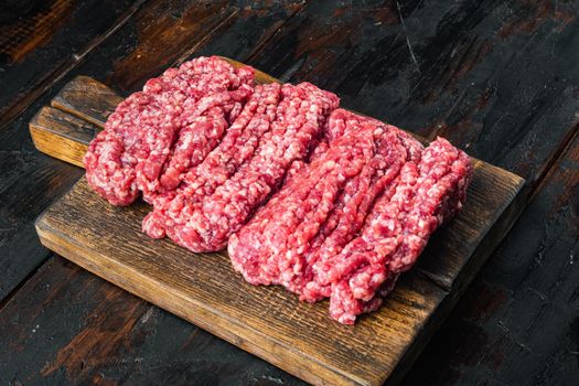 Fresh raw minced beef, ground meat, on old dark wooden table background