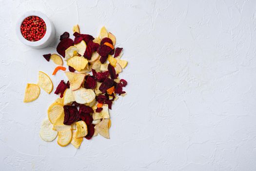 Dried vegetables chips from carrot, beet, parsnip and other vegetables set, on white stone table background, top view flat lay, with copy space for text