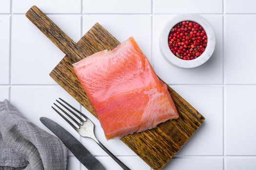 Fresh salmon fillet cut, on white ceramic squared tile table background, top view flat lay