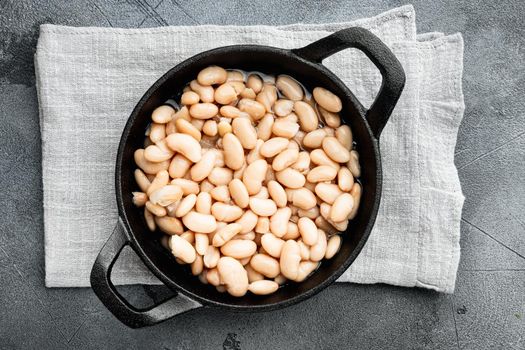 White canned beans set, in cast iron frying pan, on gray stone background, top view flat lay