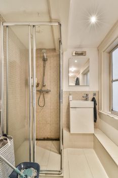 Interior of contemporary bathroom with shower, toilet and sink in minimal style in flat