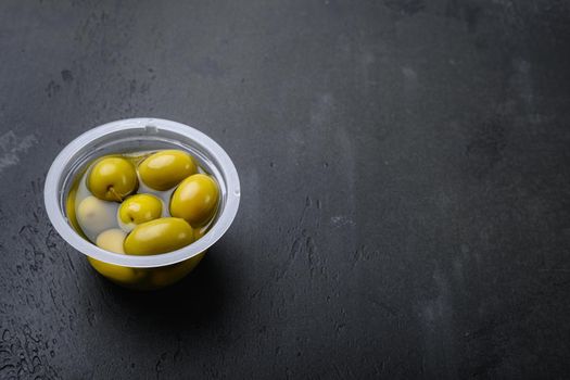 Greek green olives, on black dark stone table background, with copy space for text