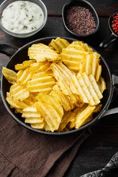 Delicious crispy potato chips set, with sour cream, on old dark wooden table