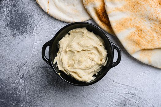 Bowl of hummus, creamy vegetarian food, on gray stone table background, top view flat lay