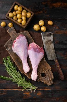 Raw turkey drumsticks with thyme, pepper set, on old dark wooden table background, top view flat lay, with copy space for text