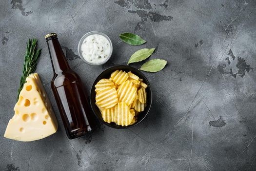 Potatoe chips set with Cheese and Onion, with dipping sauces, and bottle of beer, on gray stone background, top view flat lay, with copy space for text