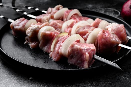 Skewer with raw kebab pork meat and onion set, on black dark stone table background