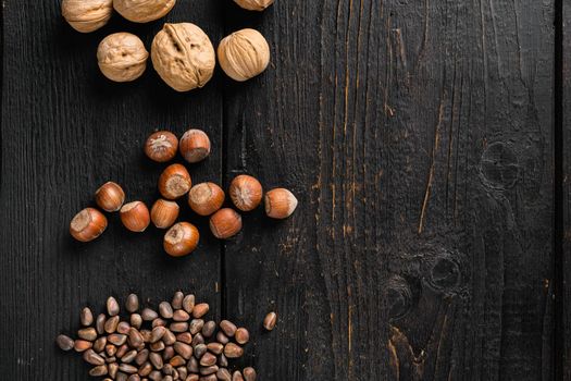 Heap or stack of hazelnuts set, on black wooden table background, top view flat lay, with copy space for text
