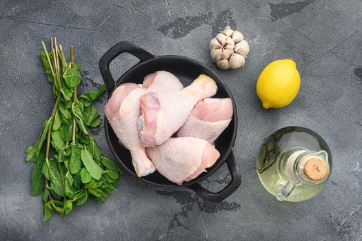 Raw marinated chicken meat, chicken legs set, on frying cast iron pan, on gray background, top view flat lay