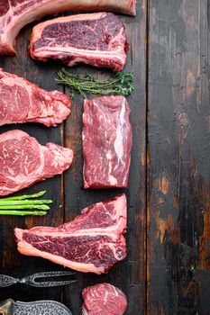 Fresh raw Prime Black Angus beef marbled and dry aged steaks set, tomahawk, t bone, club steak, rib eye and tenderloin cuts, on old dark wooden table background, top view flat lay, with copy space for text
