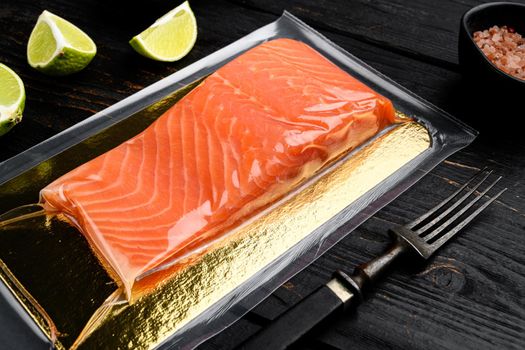 Salmon fillets in a vacuum package set, with herbs, on black wooden table background