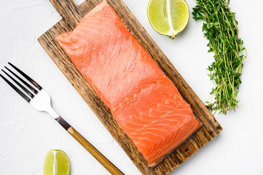 Portioned raw salmon fillet set, with herbs, on white stone table background, top view flat lay