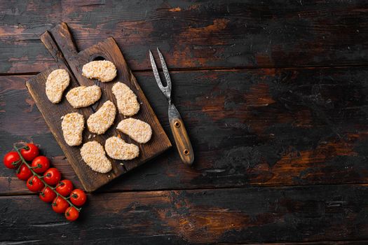 Chicken nuggets uncooked, on old dark wooden table background, top view flat lay, with copy space for text