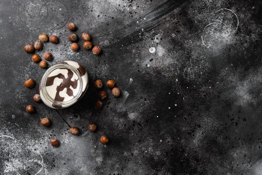 Chocolate hazelnut in jar with nuts set, on black dark stone table background, top view flat lay, with copy space for text