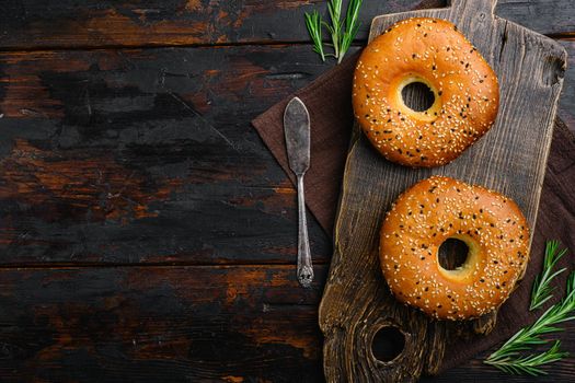 Fresh Sesame Bagel, on old dark wooden table background, top view flat lay, with copy space for text