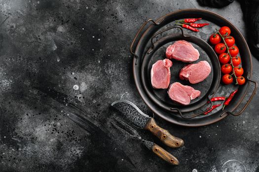 Pork tenderloin. Fresh raw meat prepared for cooking, on black dark stone table background, top view flat lay, with copy space for text