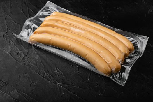 Vacuum chicken sausage pack set, on black dark stone table background, with copy space for text