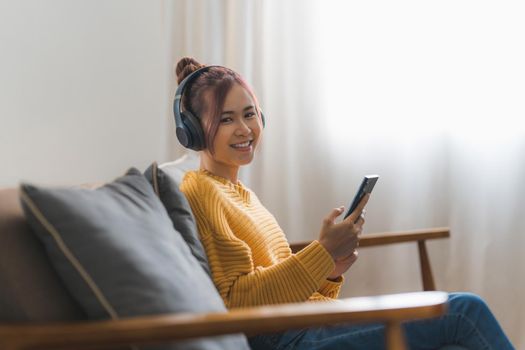 Portrait of Happy Asian artist woman using smart phone and listen music at home. Relax concept