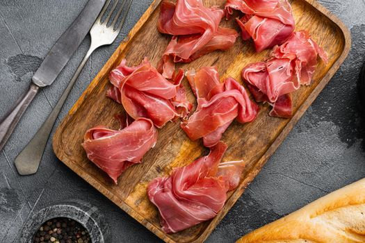 Fresh slices jamon, on gray stone table background, top view flat lay