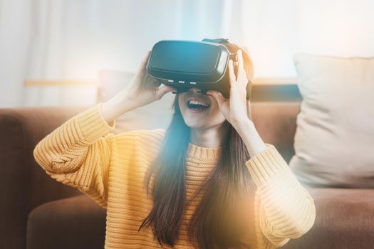 Exciting asian woman with wearable VR headset playing sport gaming online in living room at home