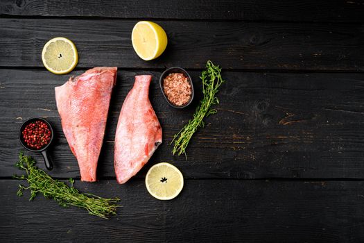 Raw red perch or sea bass fish set, on black wooden table background, top view flat lay, with copy space for text