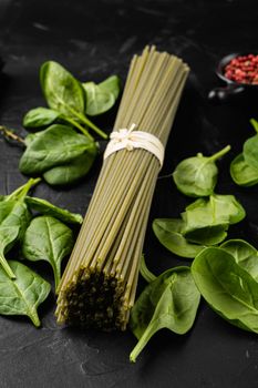 Raw dry green spaghetti with spinach set, on black dark stone table background