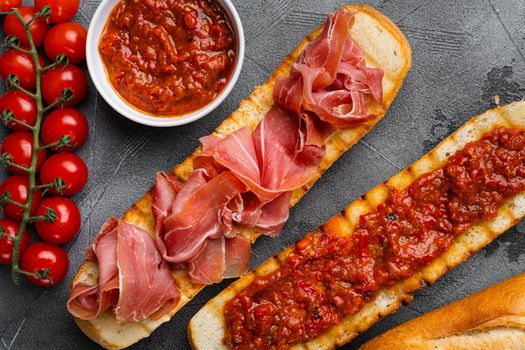 Spanish tomato and jamon toast, traditional breakfast, on gray stone table background, top view flat lay