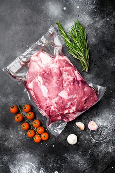 Fresh raw mutton shoulder meat set, with ingredients and herbs, on black dark stone table background, top view flat lay