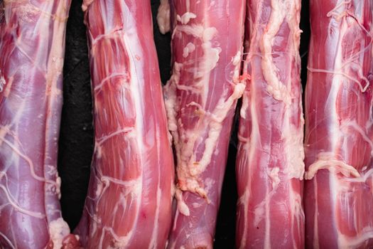 Duck necks raw, freshly set, on black dark stone table background, top view flat lay