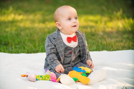 boy sitting on a white blanket with toys