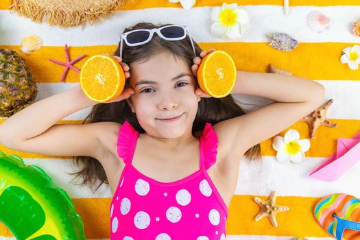 Child girl on a beach towel by the sea. Selective focus. Kid.