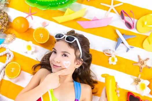 A child girl smears sunscreen on her skin. Selective focus. Kid.