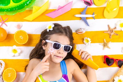 A child girl smears sunscreen on her skin. Selective focus. Kid.