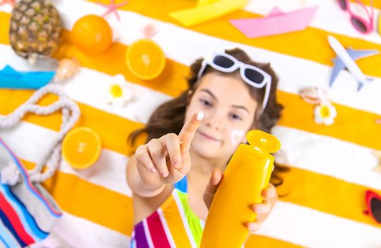 A child girl smears sunscreen on her skin. Selective focus. Kid.
