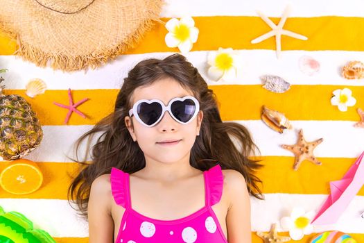 Child girl on a beach towel by the sea. Selective focus. Kid.