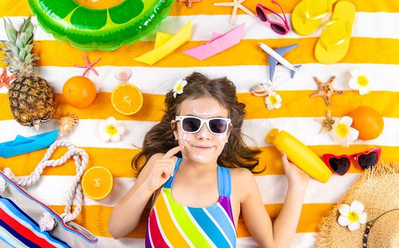 A child girl smears sunscreen on her skin. Selective focus. Kid.