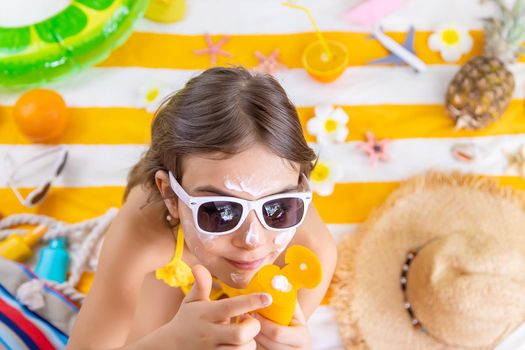 A child girl smears sunscreen on her skin. Selective focus. Kid.