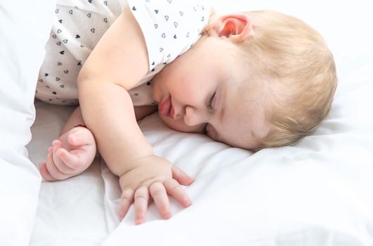 Baby sleeps on a white bed. Selective focus. Child.